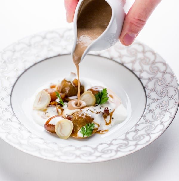 a person pouring sauce on a plate with food