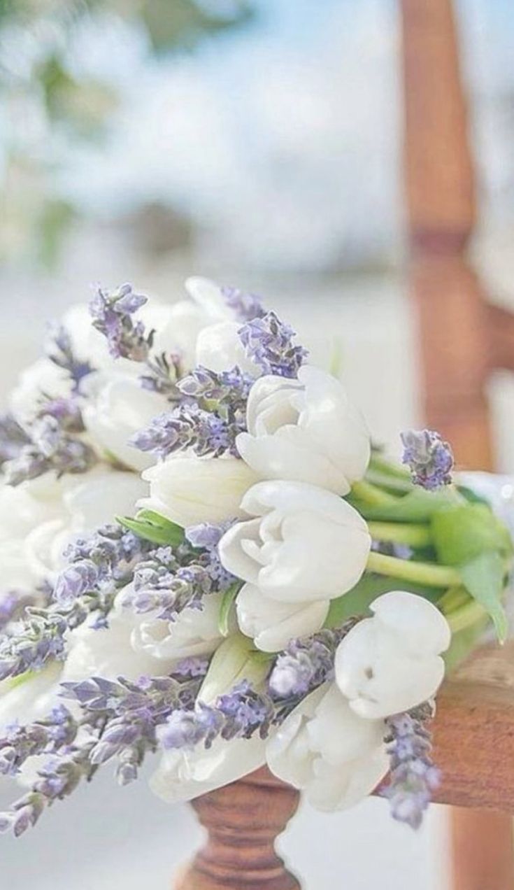 a bouquet of white tulips and lavender on a wooden chair with the background blurry