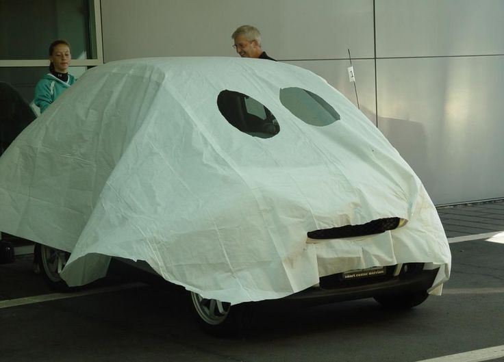 two people sitting on the back of a car covered in a sheet