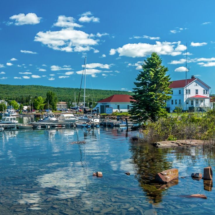 a body of water with boats in it and houses on the other side, surrounded by trees