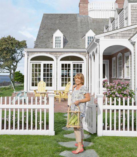 a woman standing in front of a white house