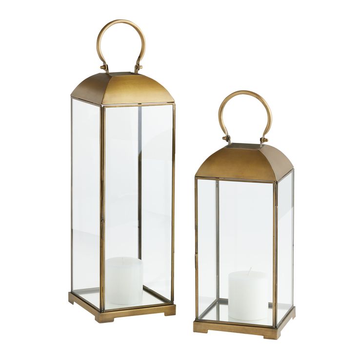 two brass colored lanterns with white candles