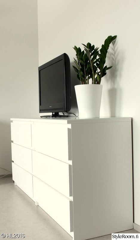 a television sitting on top of a white dresser next to a plant in a vase