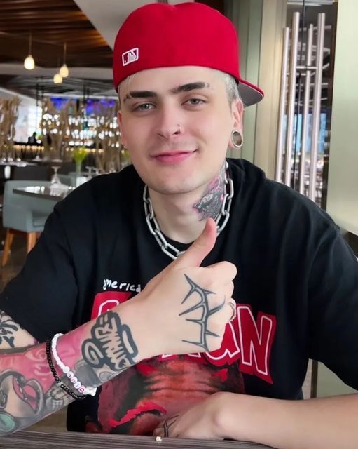 a man sitting at a table wearing a red hat and giving the thumbs up sign