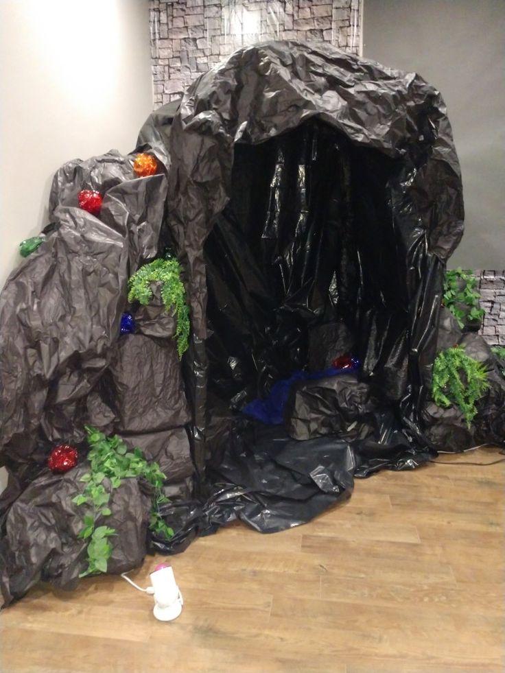 an indoor play area with black plastic bags and plants on the ground in front of it