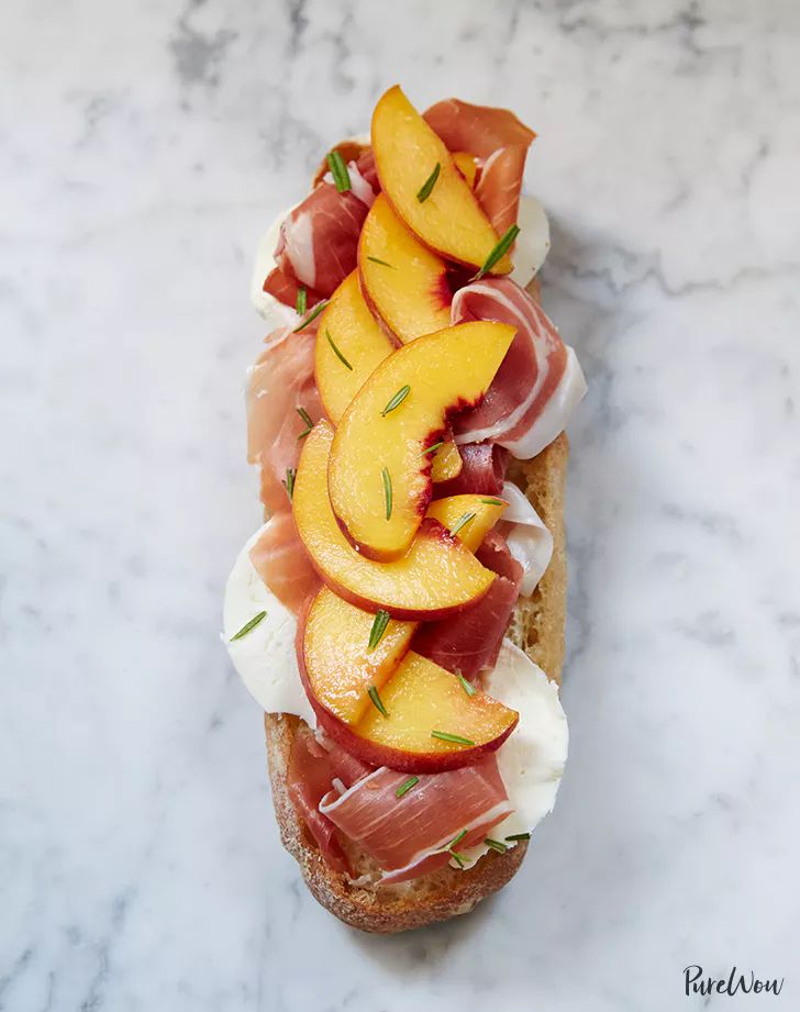 a sandwich with peaches and prosciutto on it sitting on a marble surface