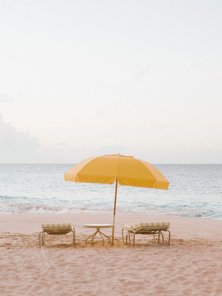 two chairs and an umbrella on the beach