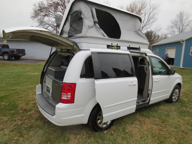 a white van is parked in the grass with it's doors open and its roof opened