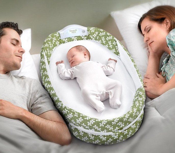 a man and woman laying in bed next to a baby sleeping on it's side