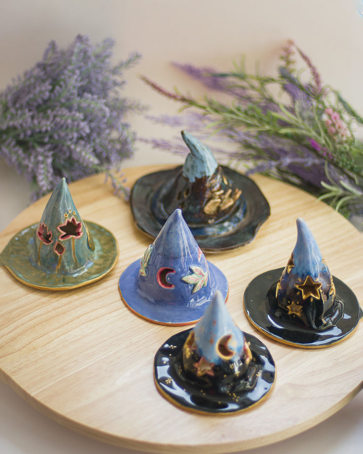 four small witches hats sitting on top of a wooden tray next to lavenders and purple flowers