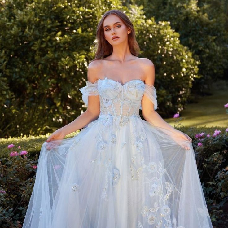 a woman in a white wedding dress with flowers on the skirt is posing for a photo