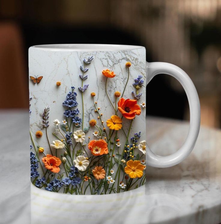 a mug with flowers painted on it sitting on a table