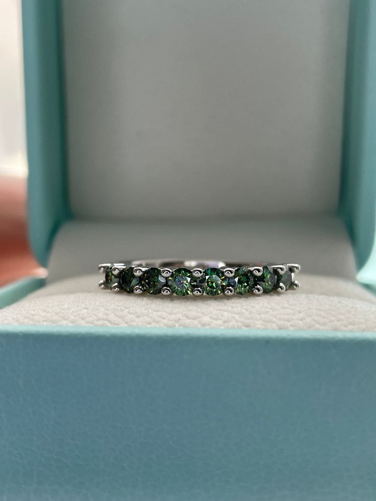 an emerald colored ring sits in a blue box