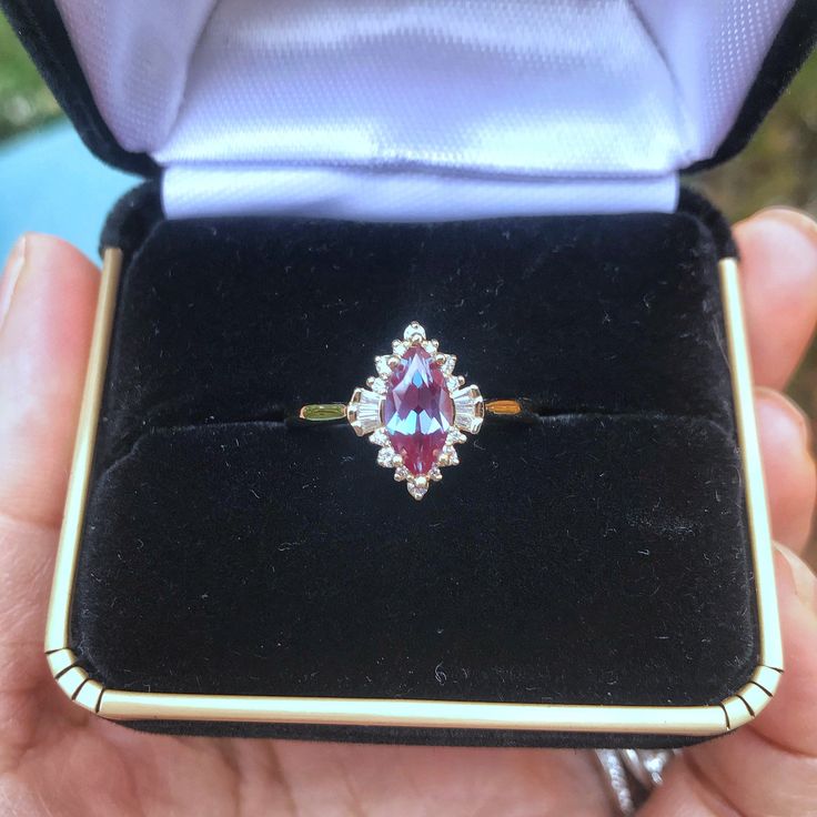 An extraordinary Contemporary Art Deco Marquise Shaped Alexandrite Engagement ring set in 14K gold enveloped in dynamic shapes of diamonds, classy and unique for that special somebody. Pictures don't do this ring justice! Only one ring in 14k Yellow gold is in stock. Check out Instagram page for more photos of this ring in different metal and stone: https://www.instagram.com/p/Bt60PmMFuEJ/ ♦ Main Ring Information ♦ Center Stone: Chatham alexandrite, Marquise Faceted Cut, 10x5mm, Green to purple( Formal Marquise Ruby Ring With Accent Stones, Formal Pink Marquise Diamond Ring, Fine Jewelry Cluster Ring With Gemstones For Proposal, Fine Jewelry Gemstone Cluster Ring For Proposal, Heirloom Pear-shaped Diamond Ring With Gemstone, Luxury Marquise Ruby Ring Gift, Marquise Sapphire And Diamond Ring For Gifts, Marquise Diamond Topaz Ring For Anniversary, Marquise Ruby Ring With Rose Cut Diamonds