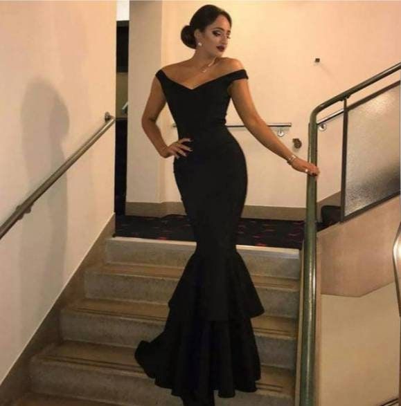 a woman in a black dress is standing on the stairs