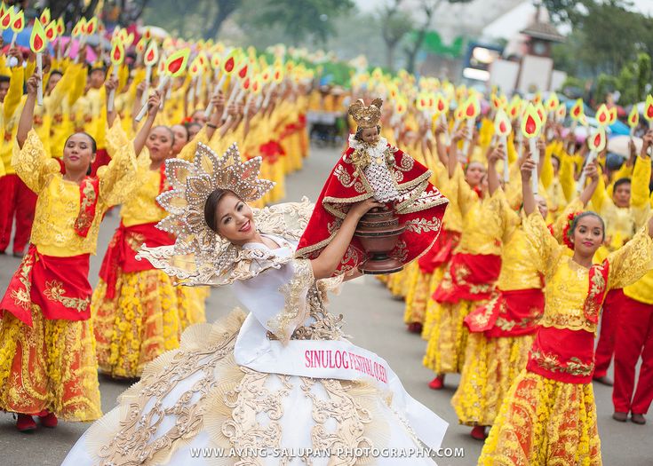 a group of people dressed in yellow and red dresses are marching down the street with their hands in the air