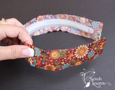 a woman is making a flowered headband out of fabric