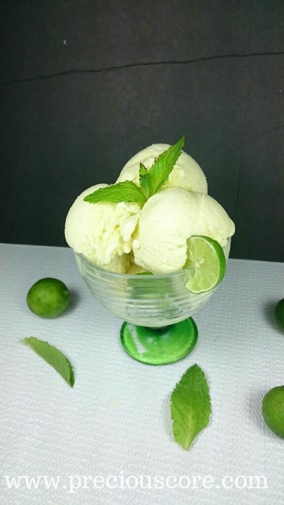 two scoops of lime ice cream in a glass bowl with mint leaves around it