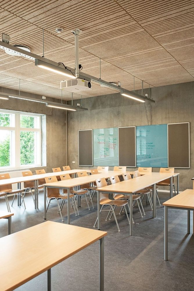 an empty classroom with wooden desks and chalkboards on the wall, in front of a large window