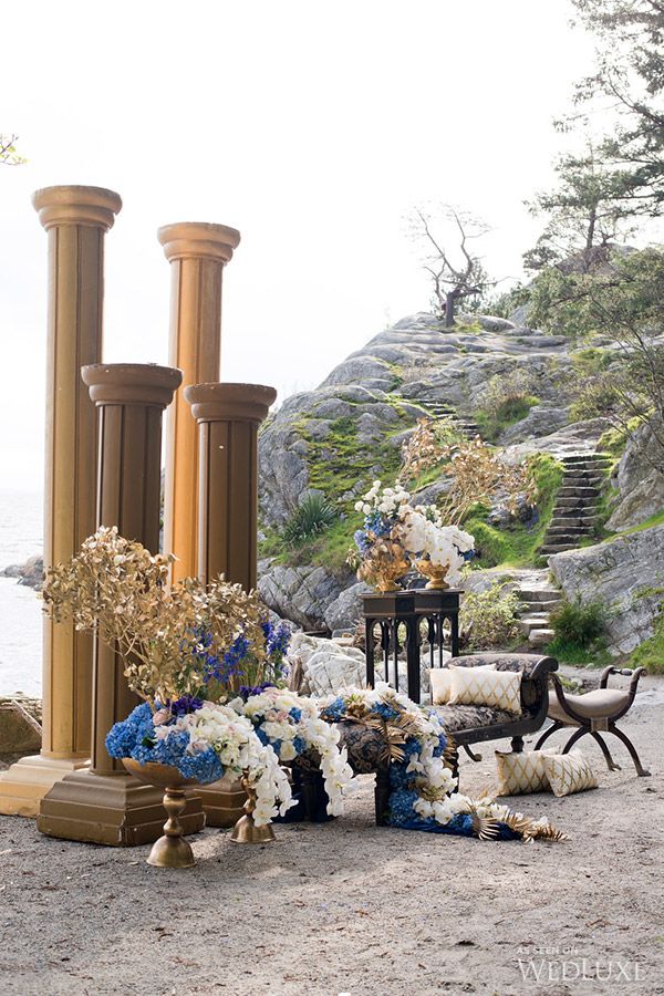 an outdoor ceremony setup with blue and white flowers on the ground next to stone steps