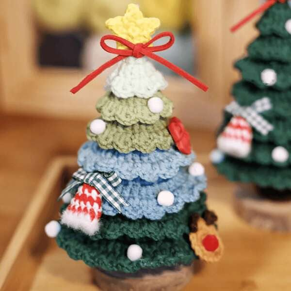 small crocheted christmas trees sitting on top of a wooden table next to each other