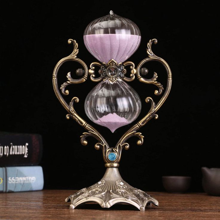 an intricately designed glass and metal stand on a wooden table with books in the background