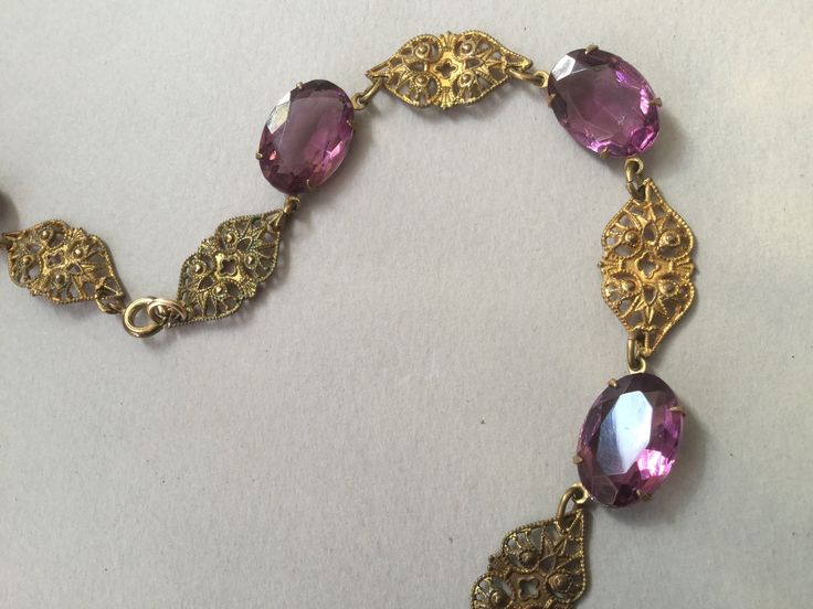 "Czech oval amethyst glass bezel/prong set cabochon collar. Wonderful Art Deco necklace that could have been made in the 20's or 30s. This is most likely made in the 1930s. Unusual bezels capture the colored glass gems that are in tandem with gilt brass filigree planks. Truly appealing necklace. This could be the antique necklace for you. Lovely condition but does show some slight greening on a couple of the gilt filigree pieces. Please look carefully. One of my favorites! 14 1/2\" long Glass an Vintage Oval Jeweled Necklaces, Vintage Oval Jeweled Necklace, Vintage Jeweled Oval Necklace, Vintage Oval Gemstone Necklace, Vintage Hallmarked Oval Cabochon Necklace, Purple Oval Filigree Jewelry, Jeweled Amethyst Jewelry For Formal Occasions, Oval Cabochon Jewelry For Party, Formal Jeweled Amethyst Jewelry