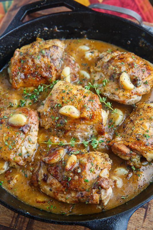 a skillet filled with meat covered in sauce and garnished with parsley