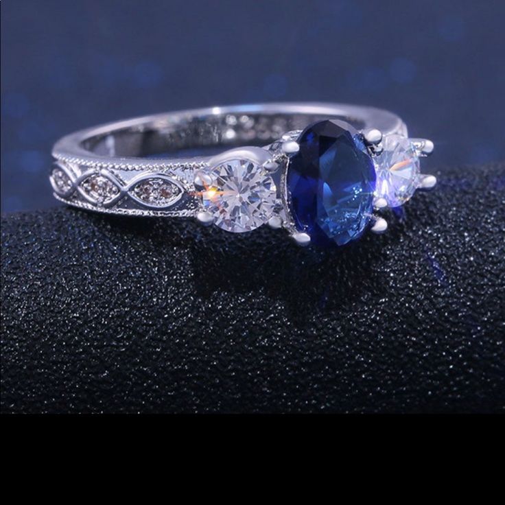 an oval shaped blue sapphire and diamond ring on a black surface with diamonds around it