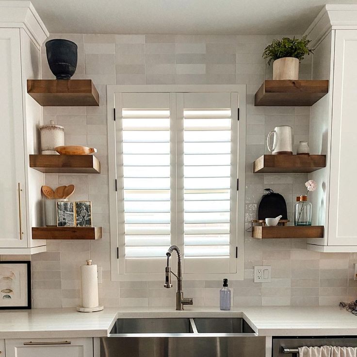 a kitchen with white cabinets and open shelving on the wall above the dishwasher