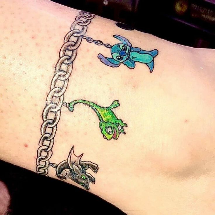 a tattoo on the leg of a woman with two cats and a dog hanging from a chain