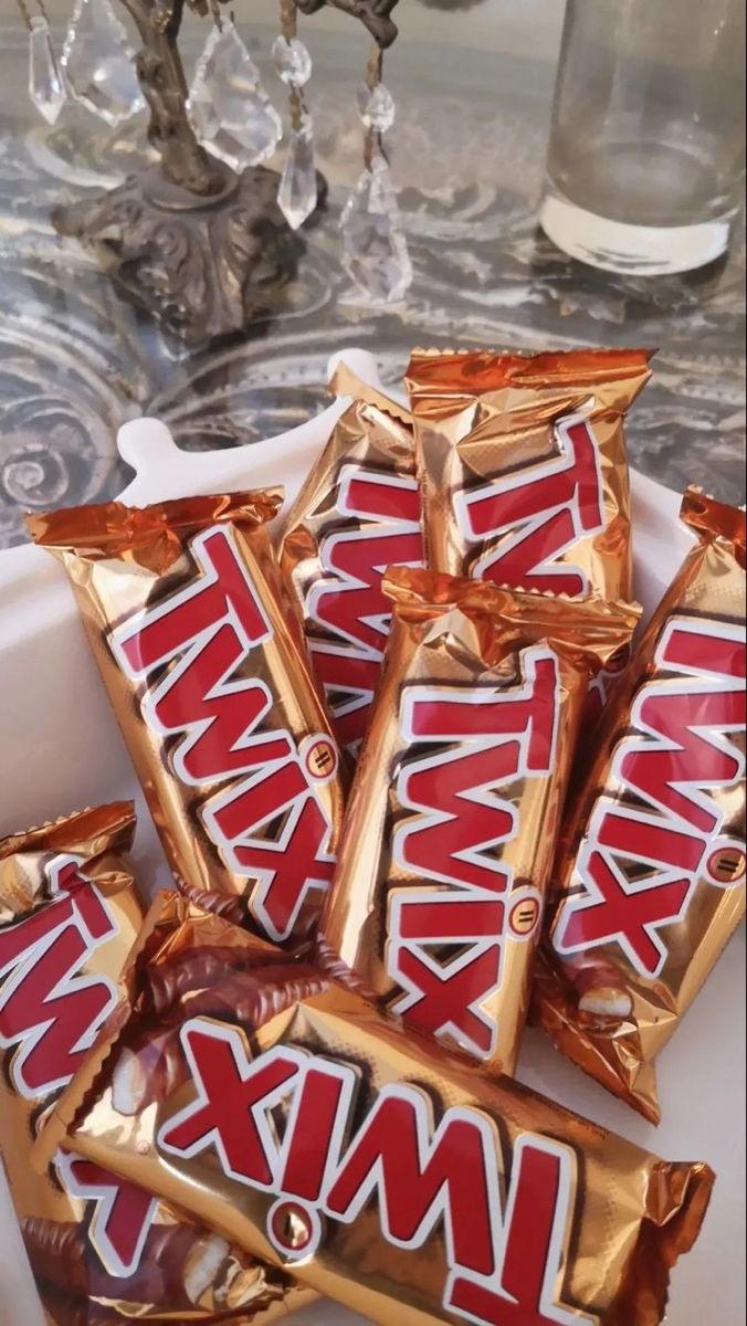 some kind of candy bar sitting on top of a white plate next to a glass vase