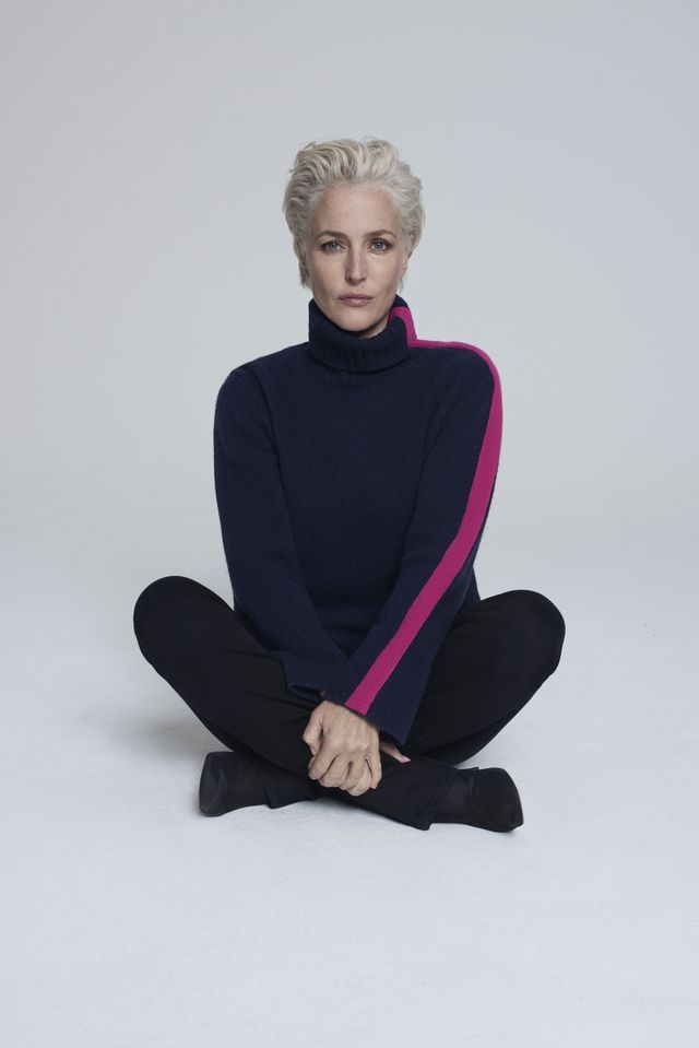 an older woman sitting on the floor wearing black pants and a blue sweater with pink trim