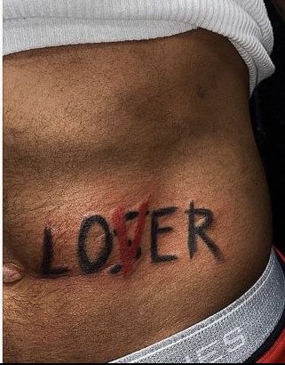 a man with a tattoo on his stomach has the word loiter written in black ink