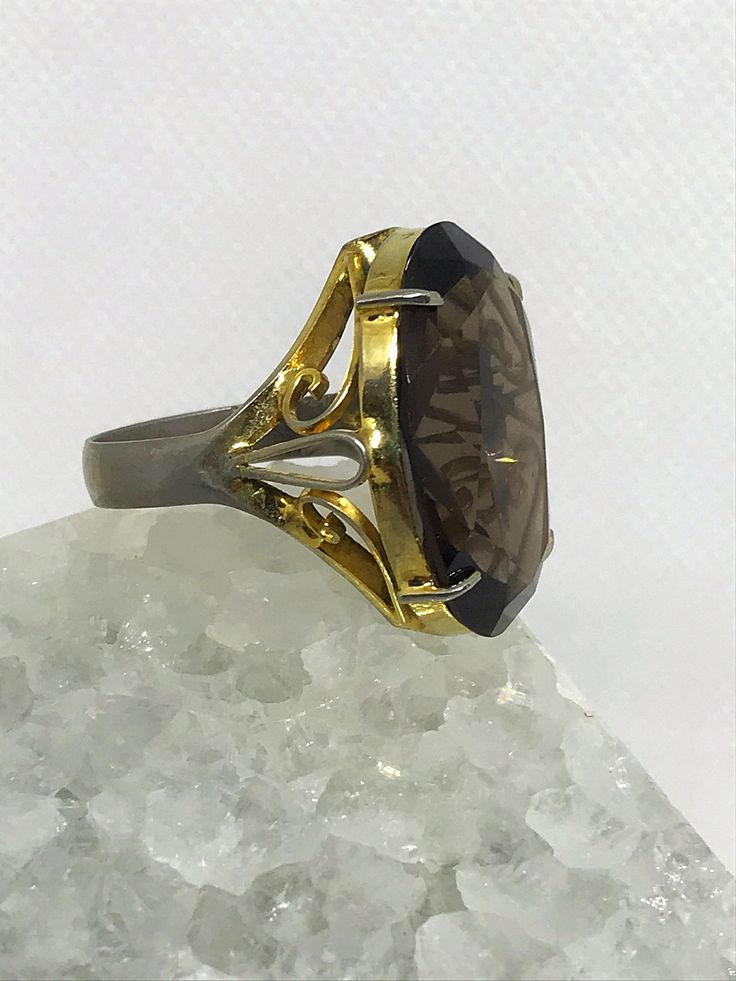 Beautiful large Smokey quartz cocktail ring. It features a gorgeous striking stone with a nicely detailed band. I'd estimate the age to be from the 1960's. Might be vermeil gold over silver as ring has some fading with gold. Ring does not have silver stamp. Size estimated to be an 8.5 to 9 woman's ring finger. Elegant Yellow Gold Ring With Large Stone, Elegant Yellow Gold Rings With Large Stone, Gold Gemstone Rings For Evening, Elegant Formal Jewelry With Large Stone, Vintage Gold Diamond Ring With Gemstone, Elegant Collectible Ring With Large Stone, Elegant Collectible Rings With Large Stone, Elegant Faceted Crystal Ring For Wedding, Classic Rings With Prong Setting For Evening