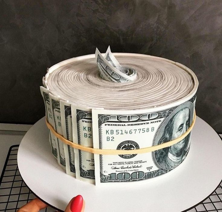 a cake made to look like a roll of money with one hundred dollars on top