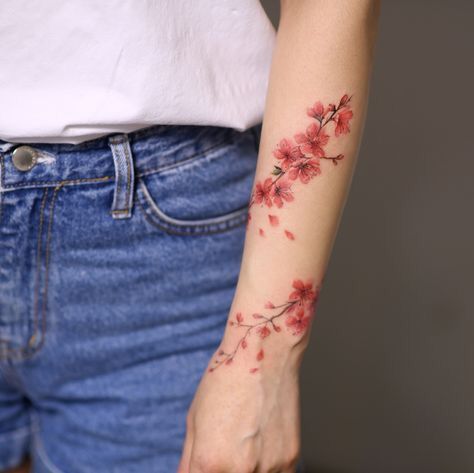 a woman's arm with red flowers tattooed on the left side of her arm