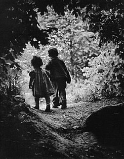 two children are walking down a path in the woods, with one child holding his hand