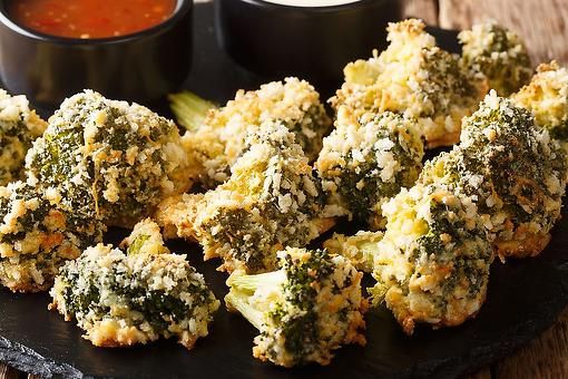 broccoli florets on a black plate with dipping sauce