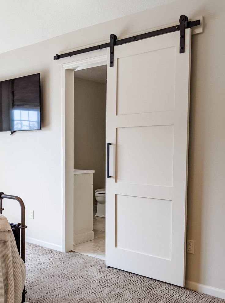 an open sliding door in a bedroom next to a bed and tv on the wall