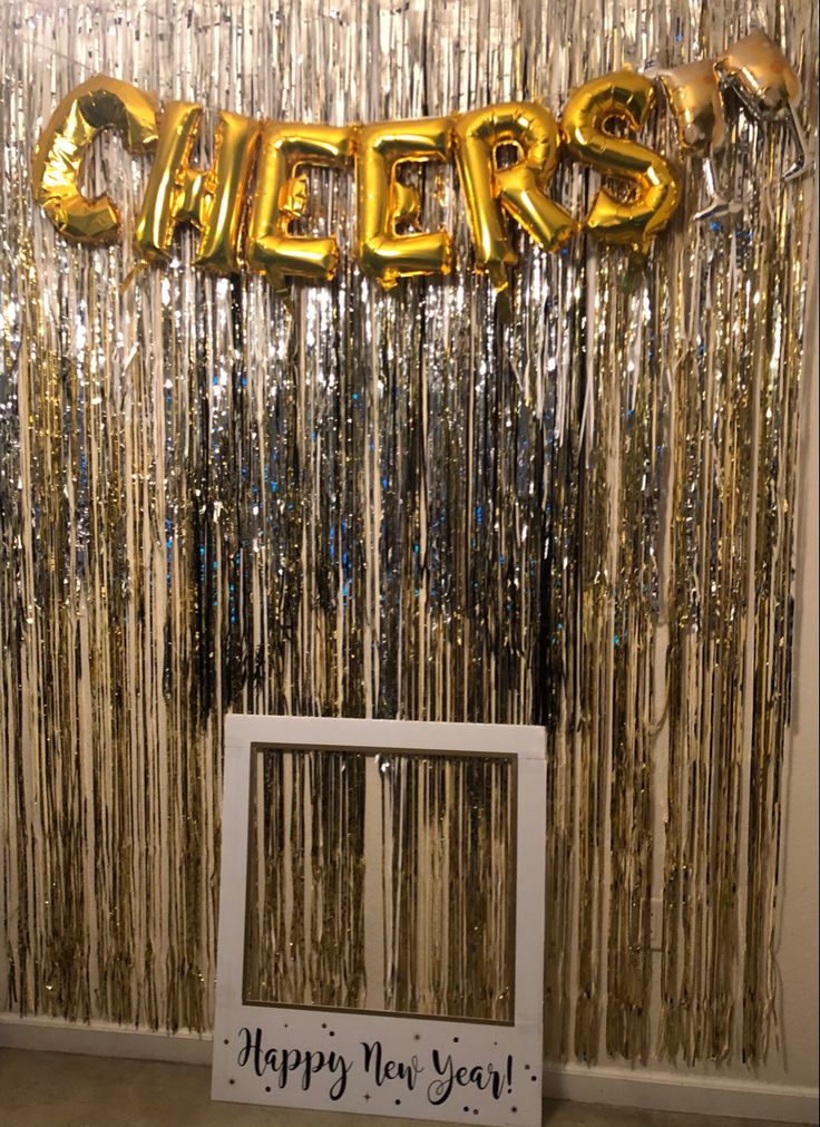 a happy new year party with gold foil streamers, balloons and a photo frame