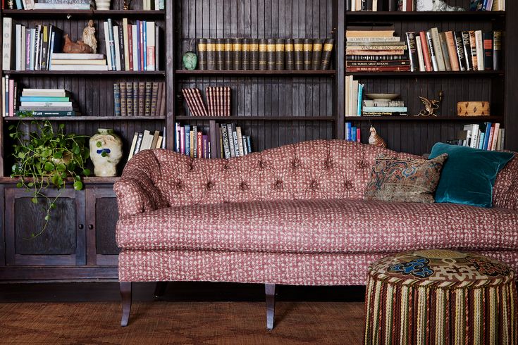 a living room filled with lots of bookshelves next to a couch and ottoman