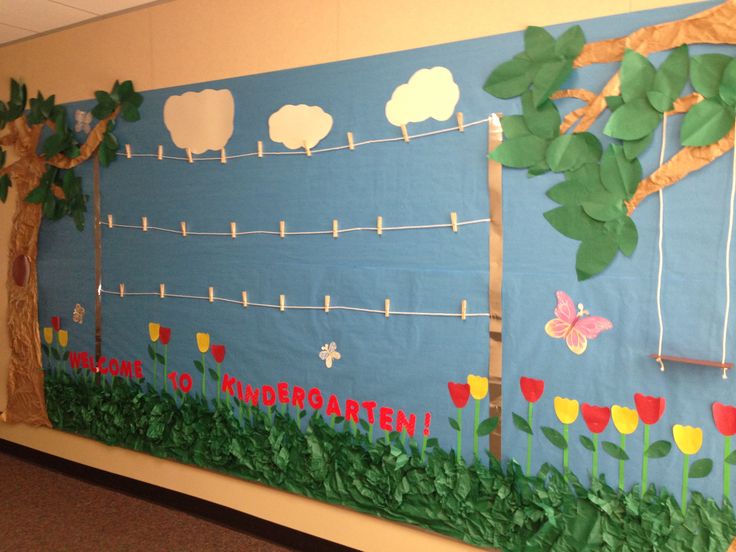 a bulletin board decorated with paper flowers and trees in the middle of a classroom hallway