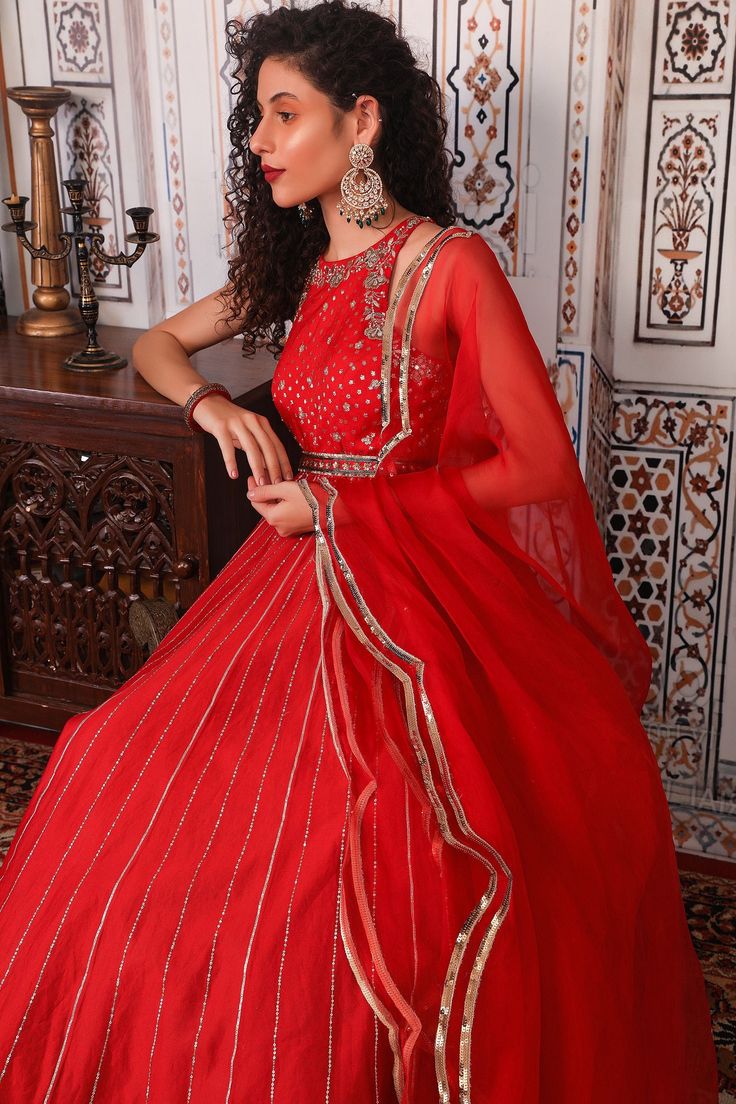 Rust anarkali with gota, nakshi, sequin embellished stripes and floral motifs. Comes with an organza dupatta with scallop hem.
Component: 2
Pattern: Embellished
Type Of Work: Gota, Nakshi, Sequin work
Neckline: Round neck
Sleeve Type: Sleeveless
Fabric: Chanderi, Organza, Semi-Crepe
Color: Red
Other Details: 
Floral motifs
Scallop hem dupatta
Sequin embellished waistband
Note: The yellow anarkali set worn by the other model is not for sale.
Occasion: Wedding - Aza Fashions Party Anarkali Set With Traditional Drape And Kundan, Chinon Salwar Kameez For Reception And Navratri, Anarkali Choli With Cutdana For Party, Anarkali Kundan Party Dress, Festive Mirror Work Salwar Kameez For Reception, Kundan Salwar Kameez For Reception And Festivals, Red Anarkali Lehenga With Mirror Work, Red Churidar With Sheer Dupatta In Chinon, Georgette Salwar Kameez For Reception And Festivals