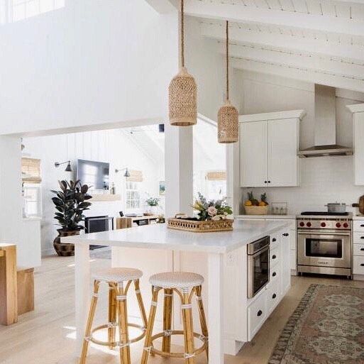 a kitchen with white cabinets and an island in front of a stove top oven next to two stools