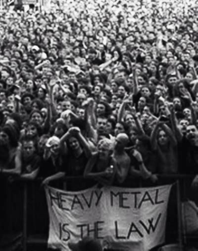 a large group of people standing in front of a crowd holding up signs that read eam metal is the law