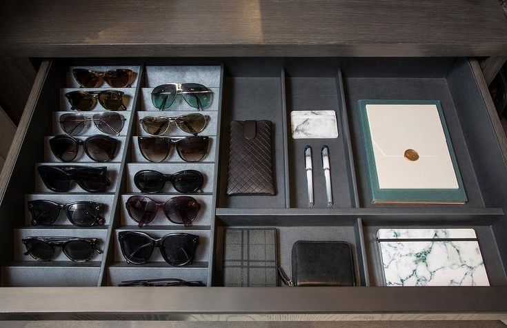 an organized drawer with sunglasses, pens and other items