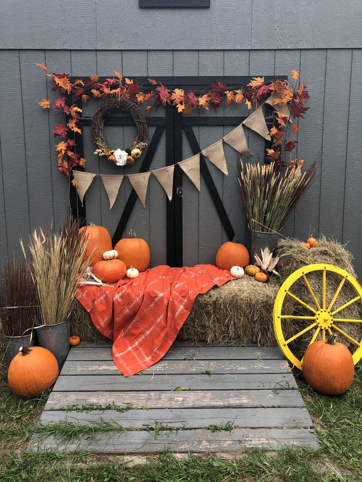 pumpkins, hay bales and fall decorations on display in front of a barn