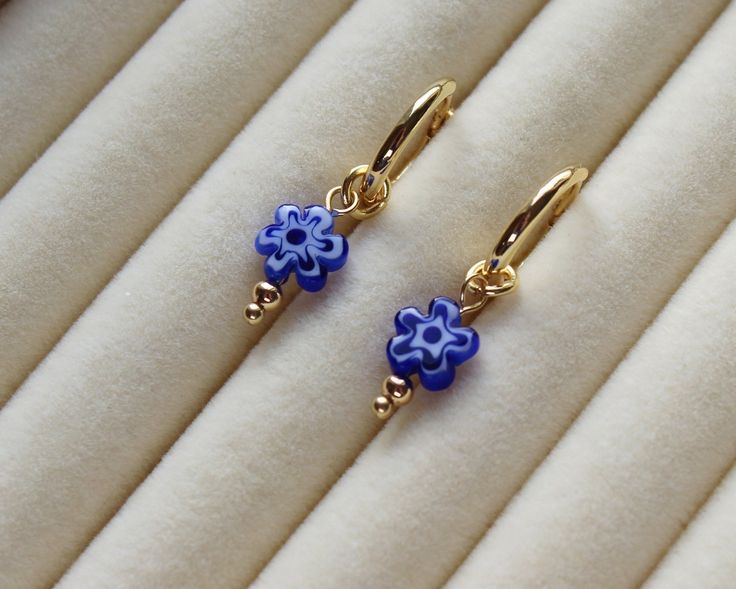 Millefiori Flower Earrings - Blue Gold Huggie Hoops Bead dimensions: 8x8x3.2mm Made with 18k gold plated hoops / hardware Beaded earrings / glass earrings Packaging: All products come with freebies and are packed by hand, so they make a great gifting experience! Postage: All orders are dispatched in 1-2 working days. Materials and Care: This item is 18K gold plated. Regularly polish and buff the metal using a soft (lint-free) cloth. Avoid contact with water / liquids. --------------------------- Huggie Jewelry With Flower Charm For Gift, Huggie Jewelry With Flower Charm As Gift, Flower Charm Huggie Earrings As Gift, Blue Huggie Earrings As Gift, Gift Jewelry Flower Charm Huggie, Huggie Earrings With Flower Charm For Gift, Blue Hypoallergenic Huggie Earrings Gift, Blue Dangle Huggie Earrings As Gift, Blue Dainty Hypoallergenic Hoop Earrings