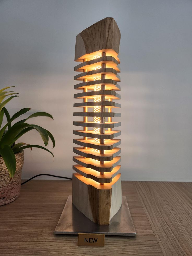 a wooden sculpture with many lights on it sitting on top of a table next to a potted plant